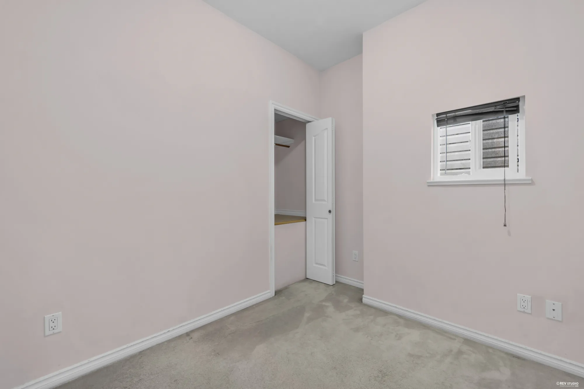 An upstairs bedroom with a shuttered window and a doorway to the hall