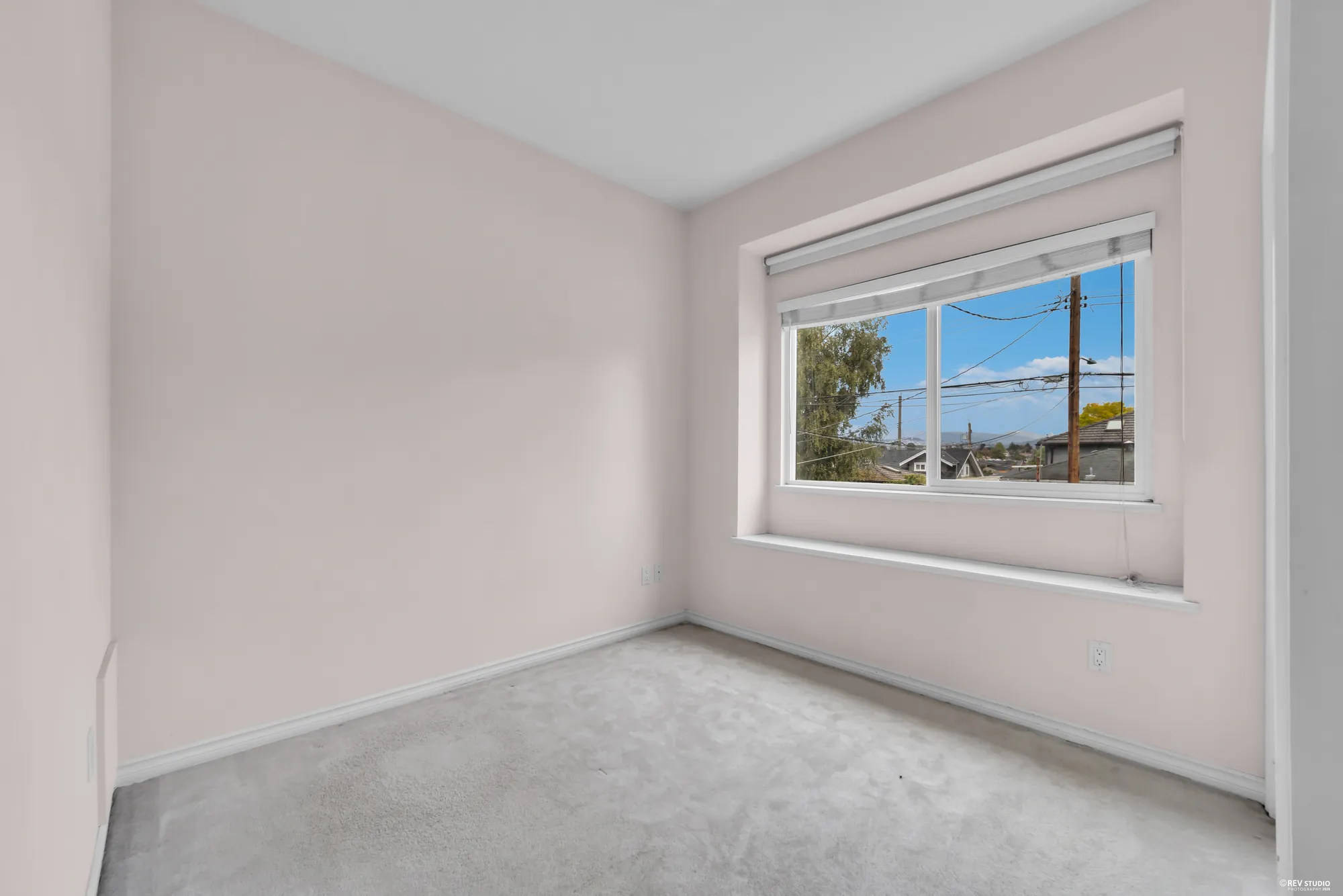 An upstairs bedroom with a window looking out over the street