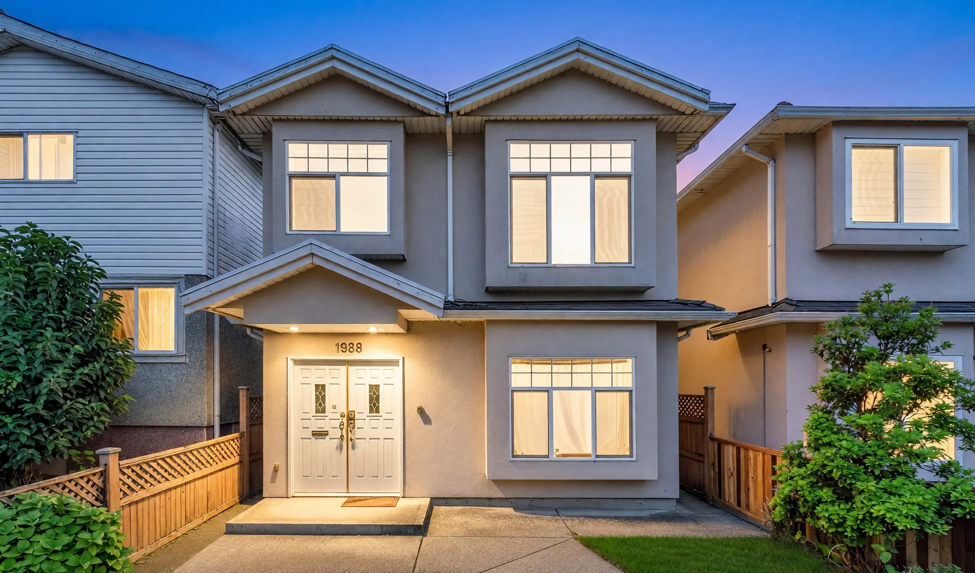 1988 Nanaimo Street from the front at dusk, the windows lit