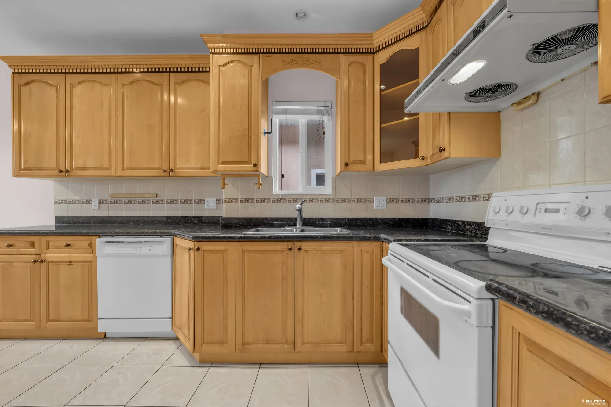 The upper kitchen in oak with granite counters, a range and a dishwasher