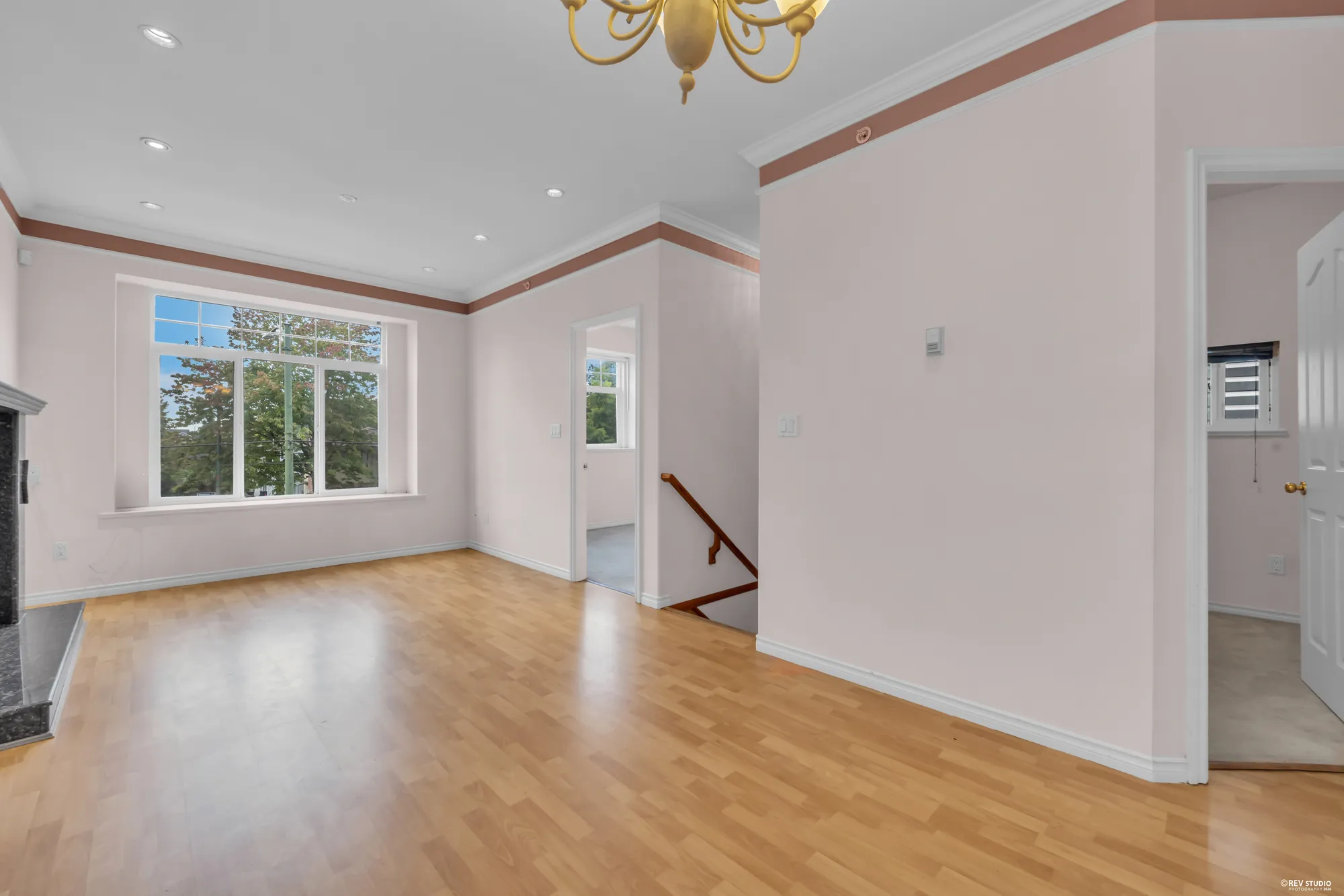 The upper living room with hardwood floors, a fireplace and windows to the street