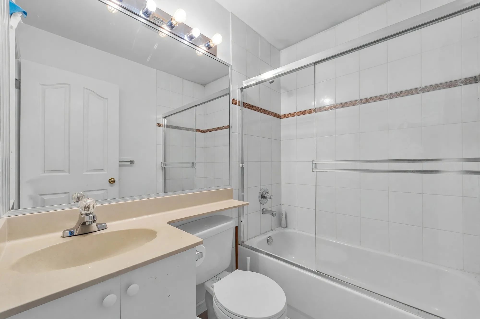 A main-floor bathroom with a tub and a sliding glass door, photographed after clutter was digitally removed