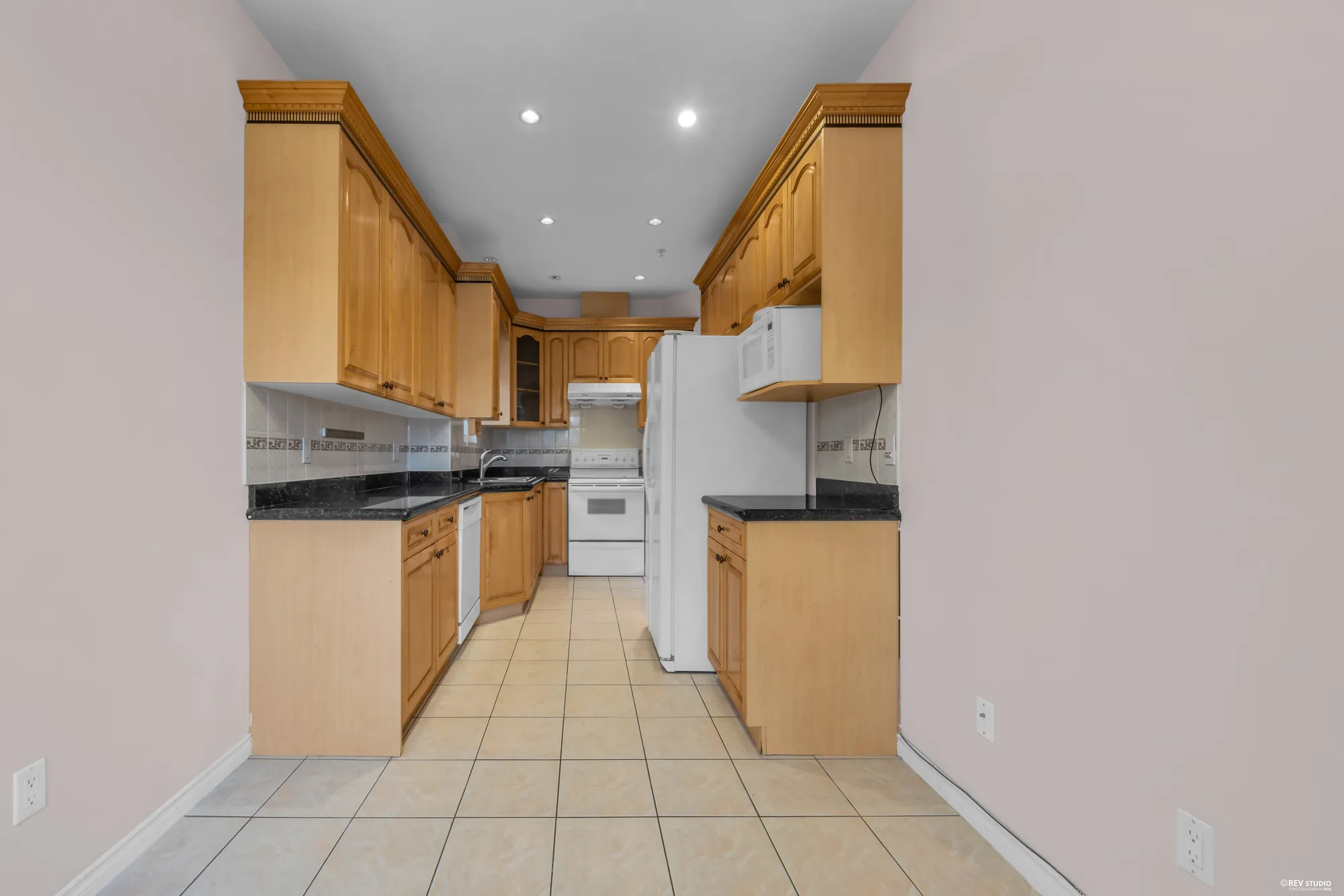 The main-floor kitchen with oak cabinets, tile floor and white appliances