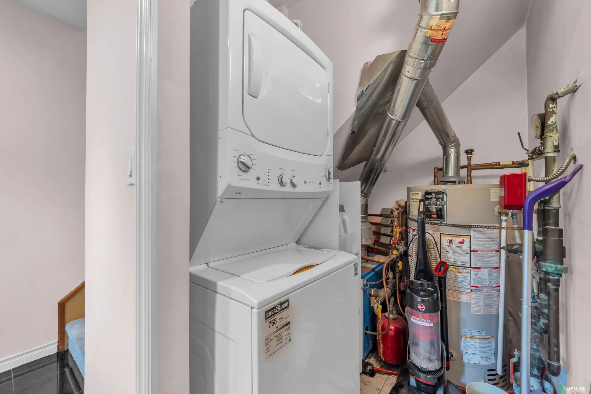 The utility area with a stacked washer and dryer and the hot water tank